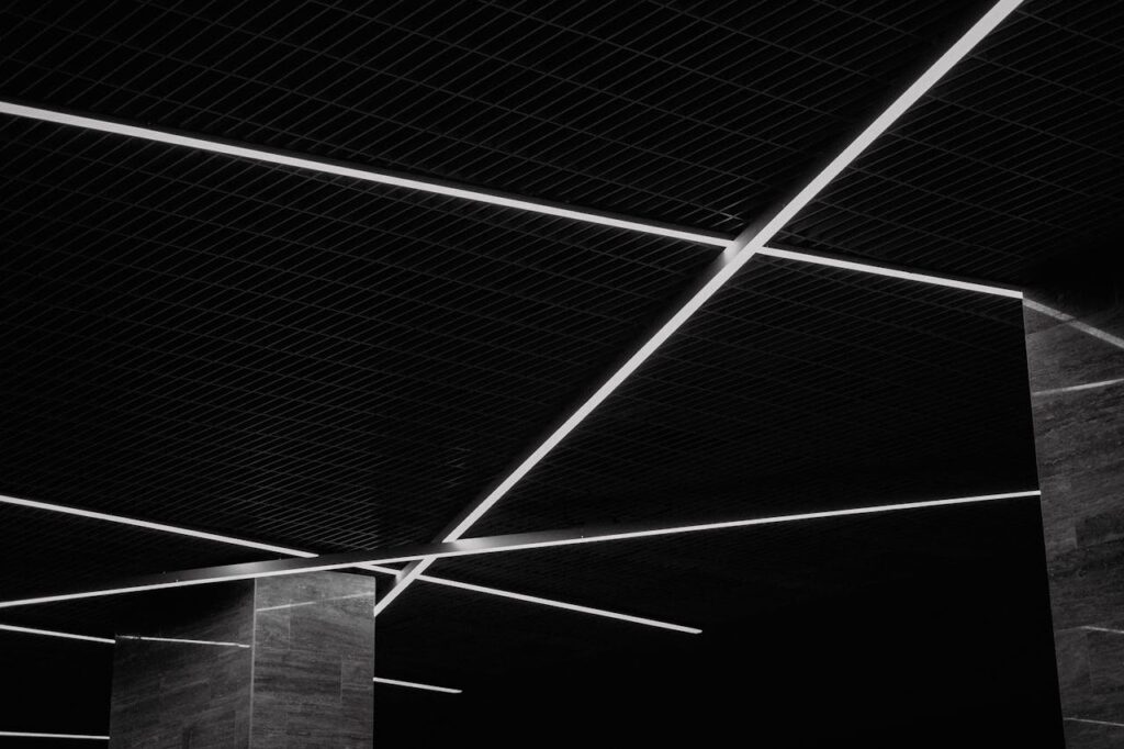 Black and white abstract view of a modern ceiling with geometric light patterns and textures.
